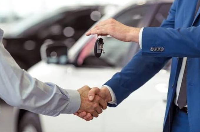 Handshake between two people as car keys are exchanged, symbolizing a car sale or purchase.