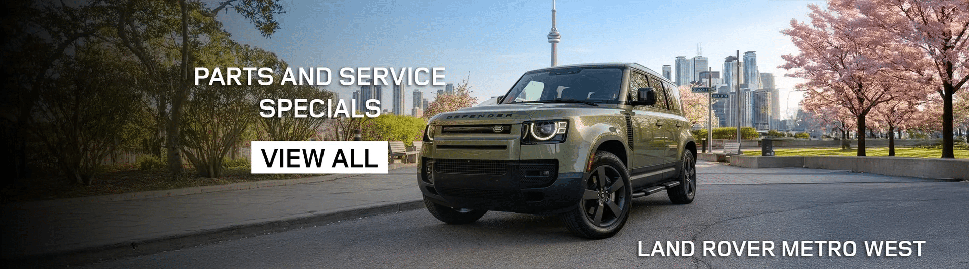 Land Rover Defender on a city street with blossoming trees, promoting parts and service specials.