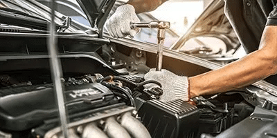 Mechanic using a wrench to work on a car engine, highlighting vehicle maintenance.